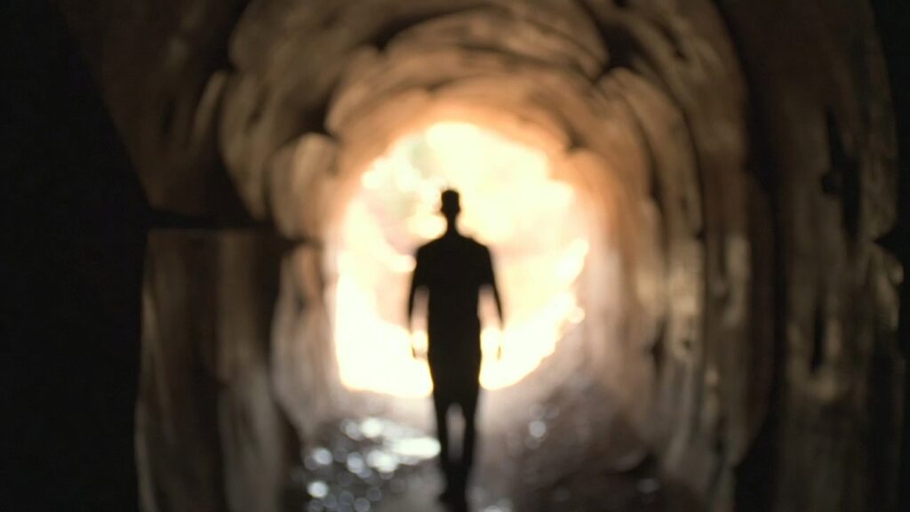 Escolhas que Transformam Seu Futuro: 7 Decisões que Podem Mudar Sua Vida Para Sempre 17 Pessoa caminhando confiante em direção à luz simbolizando coragem e decisão